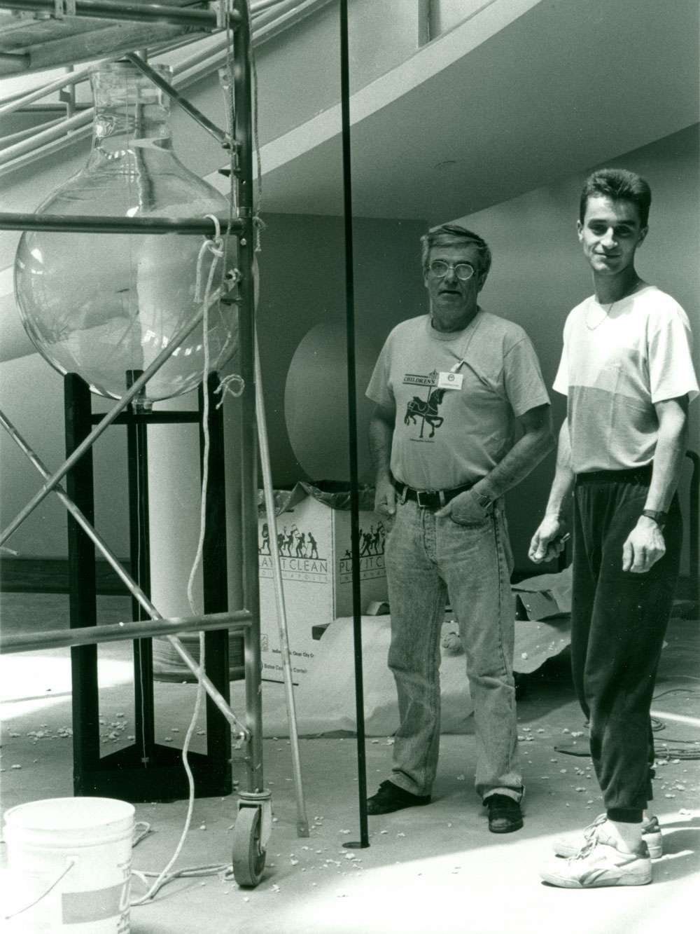 Black and white photo of Bernard Gitton and an unnamed assistant standing by the Water Clock during its assembly.